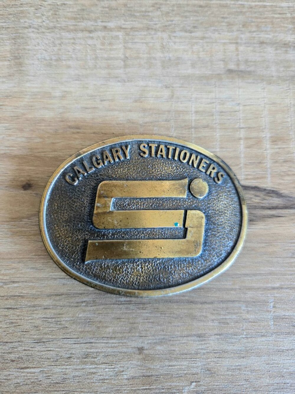Vintage Calgary Stationers Oval Brass Tone Belt Buckle with S Logo.